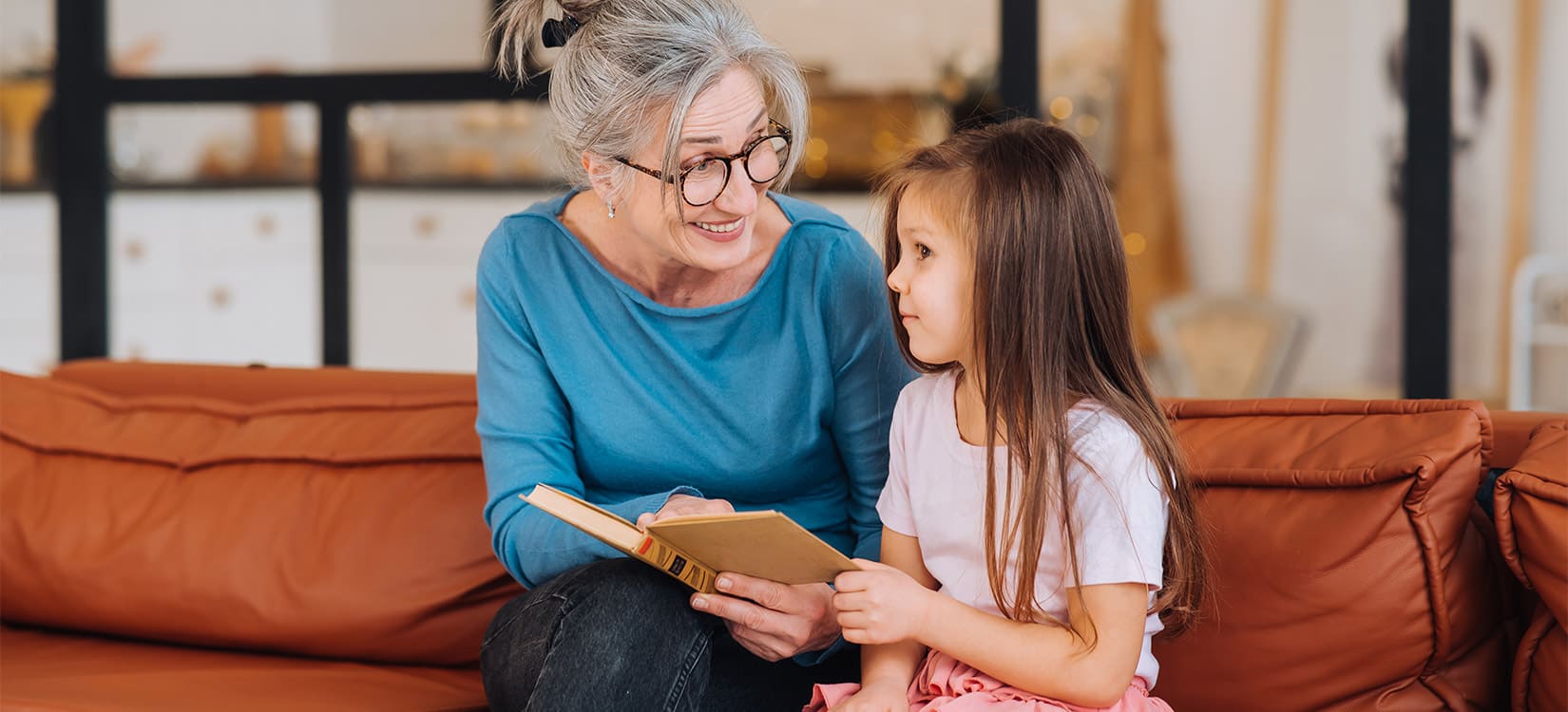 Ältere Dame hilft Mädchen beim Lesen