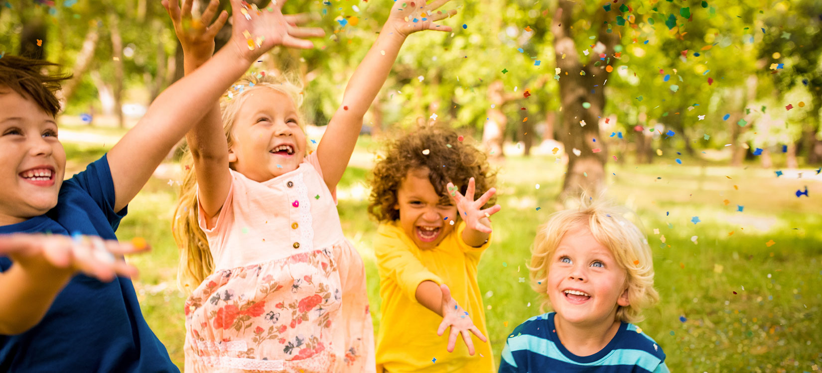 Fröliche Kinder im Park mit Confetti 